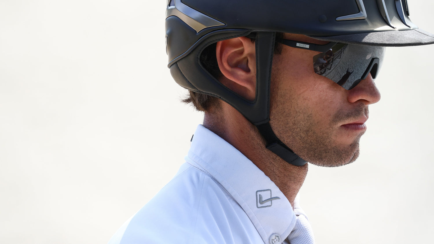 Man wearing a black helmet and sunglasses against a light background