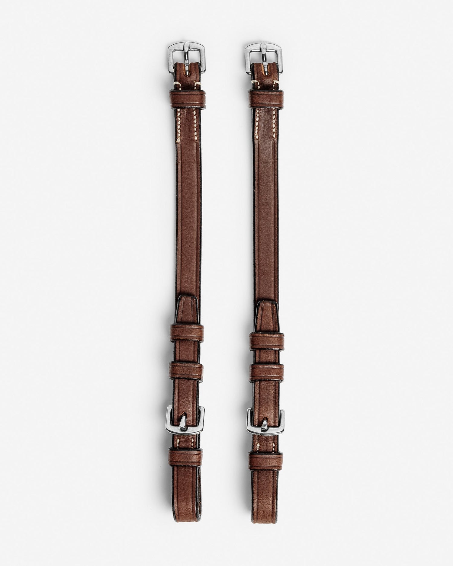 Pair of brown leather straps with silver buckles on a white background