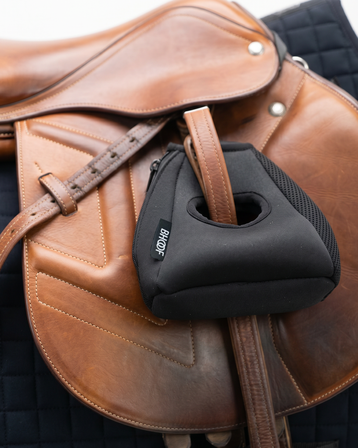 Black equestrian stirrup cover on a brown leather saddle